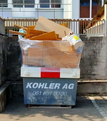 Falsch beladene Mulde mit Karton und losem Material